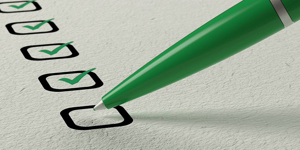Green pen checks off boxes on a paper list.