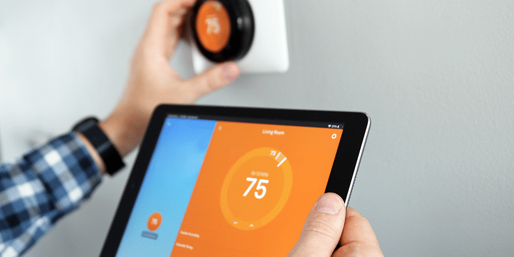 Thermostat Programming Tips Homeowner connects tablet to smart thermostat to set temperature in house.