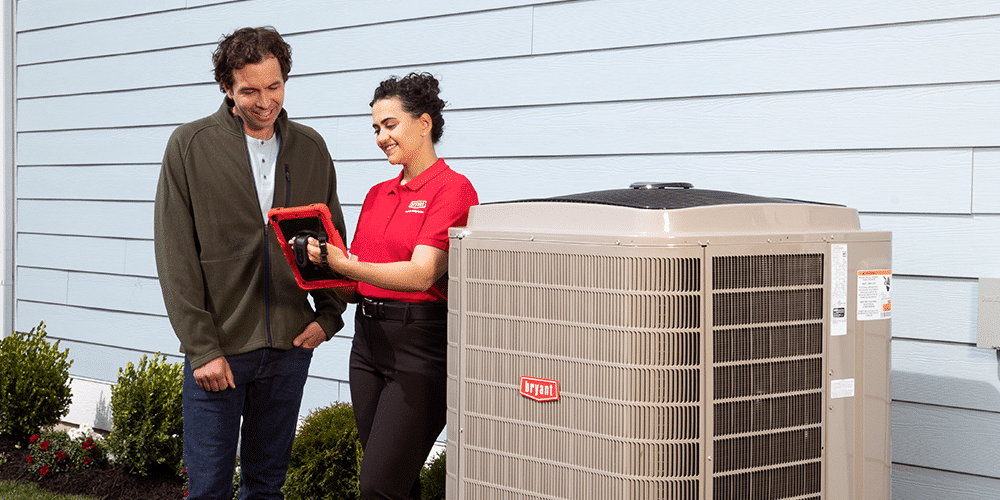 Time to Replace Your A/C Female tech in red shirt explains to male homeowner how his new air conditioner works.