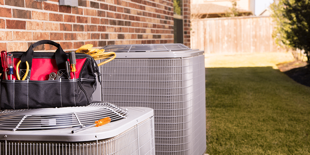 Shot of residential air conditioners with a technician’s bag of tools on top.