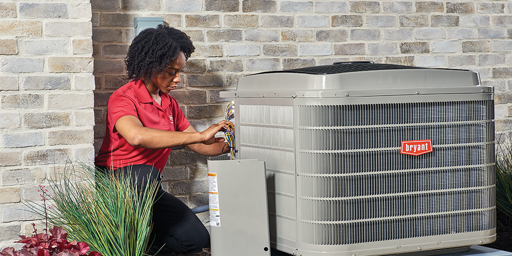 Technician performs annual AC maintenance on a cooling unit outdoors.