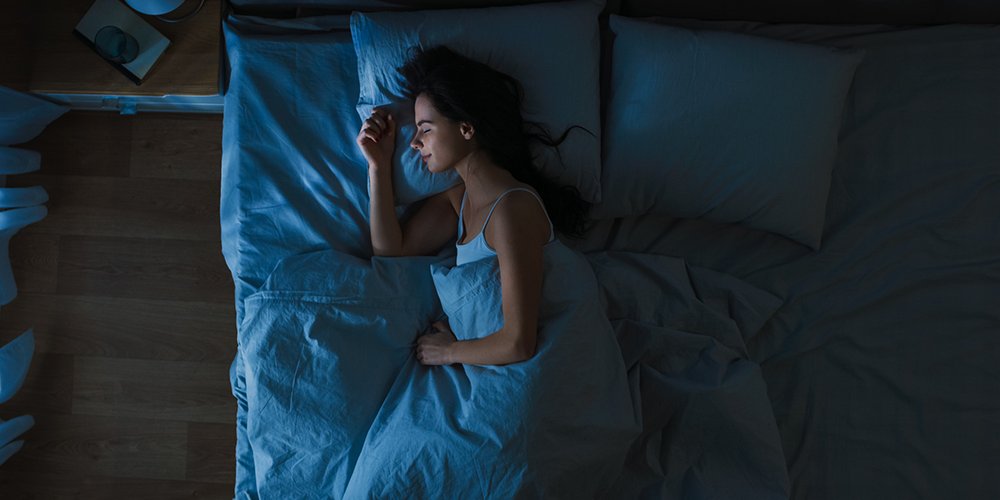 After finding the ideal temperature for sleeping, female homeowner rests comfortably in bed.